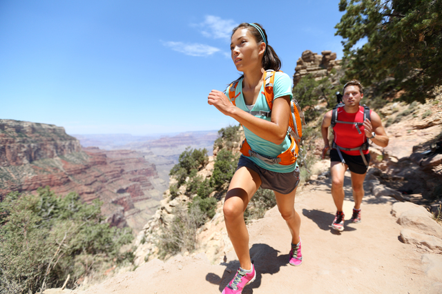 Trail running cross-country runners in race on path in Grand Canyon, USA. Fit athletes jogging and training together in beautiful nature landscape. Asian fitness woman, Caucasian fit model.
